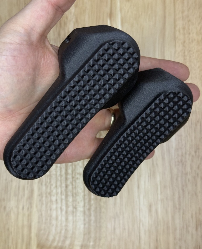 Standard-height and low-profile B&T buttpads held for scale, checkered faces