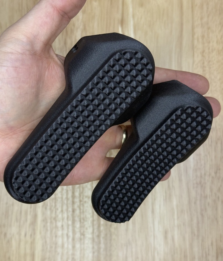Standard-height and low-profile B&T buttpads held for scale, checkered faces